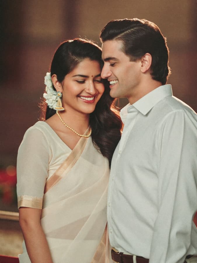 A newly engaged couple in traditional dress, laughing together in soft evening light
